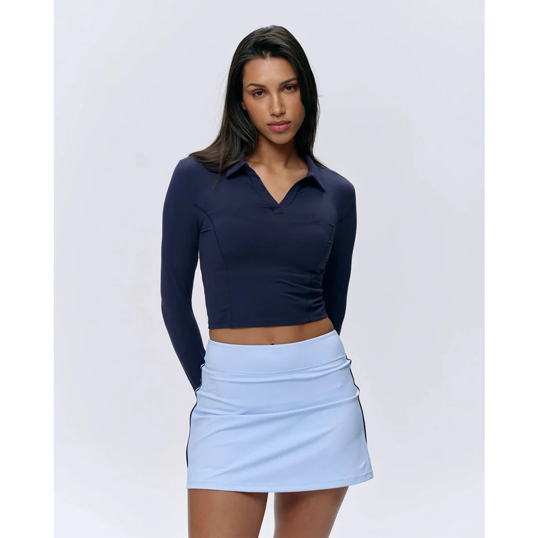 Woman wearing a navy long-sleeve top and light blue skirt on a white background