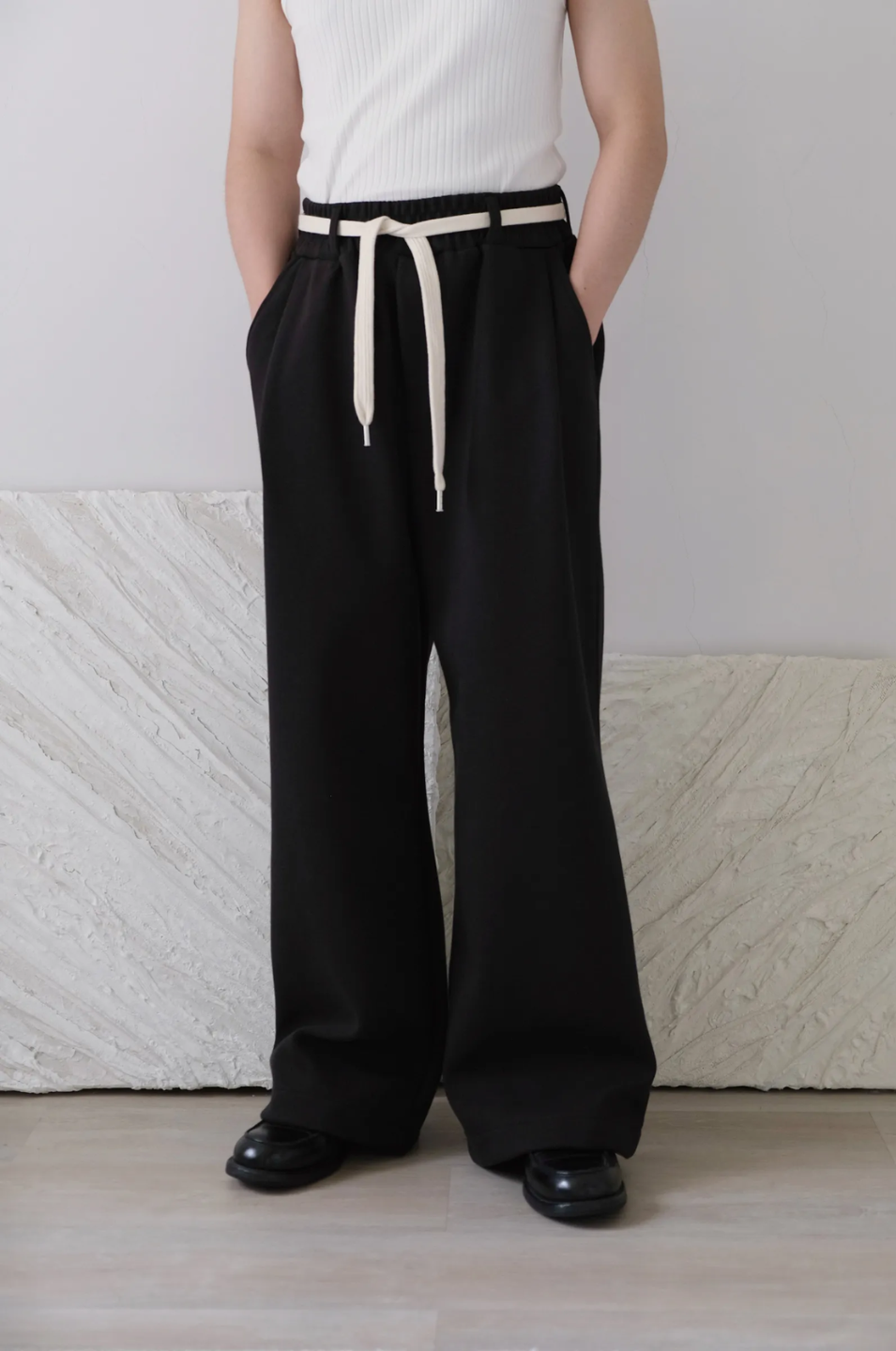 wide leg Black pants with a cotton belt, a white top, and black shoes.