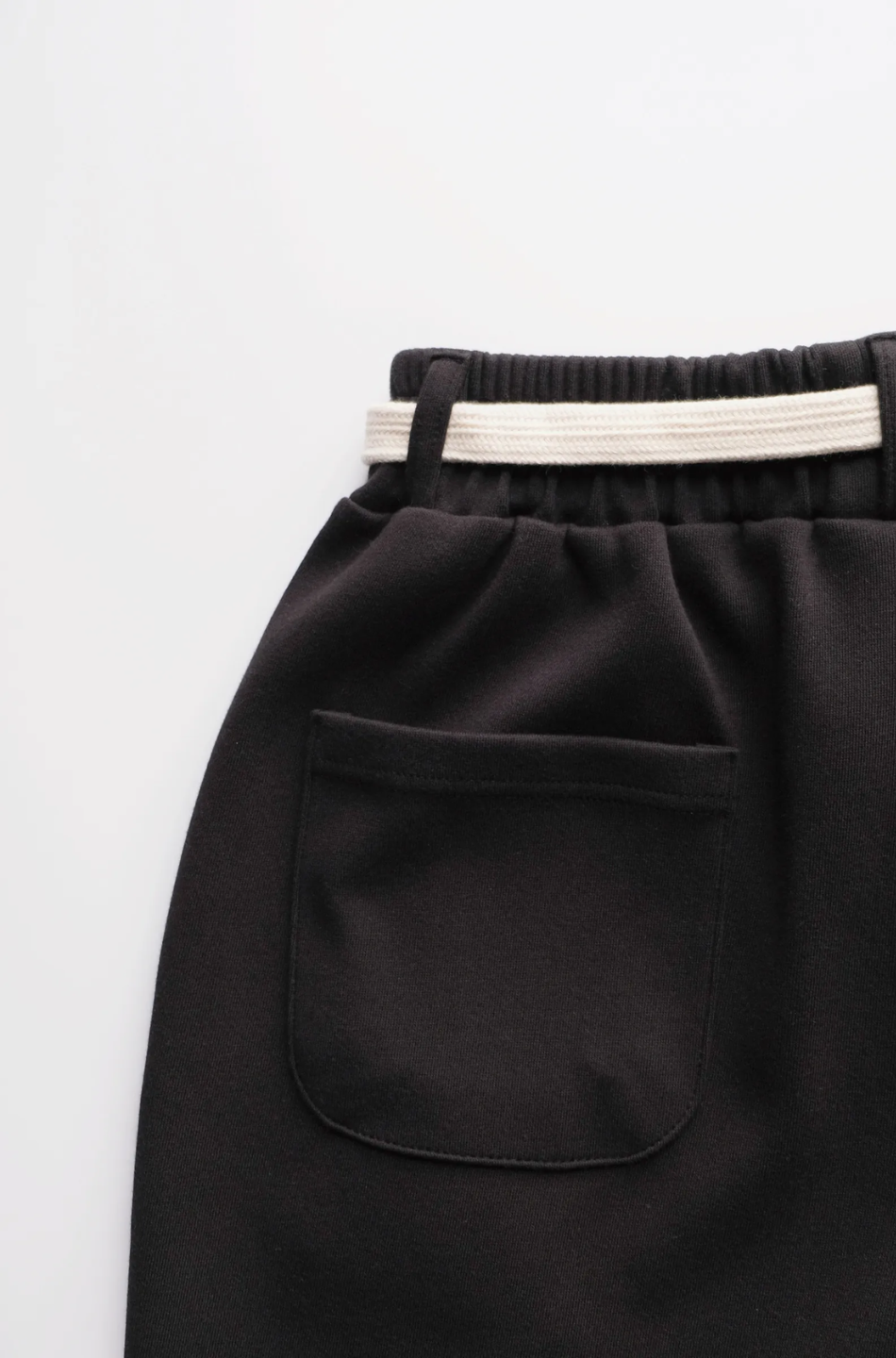 Black skirt with a pocket and white waistband on a light gray background