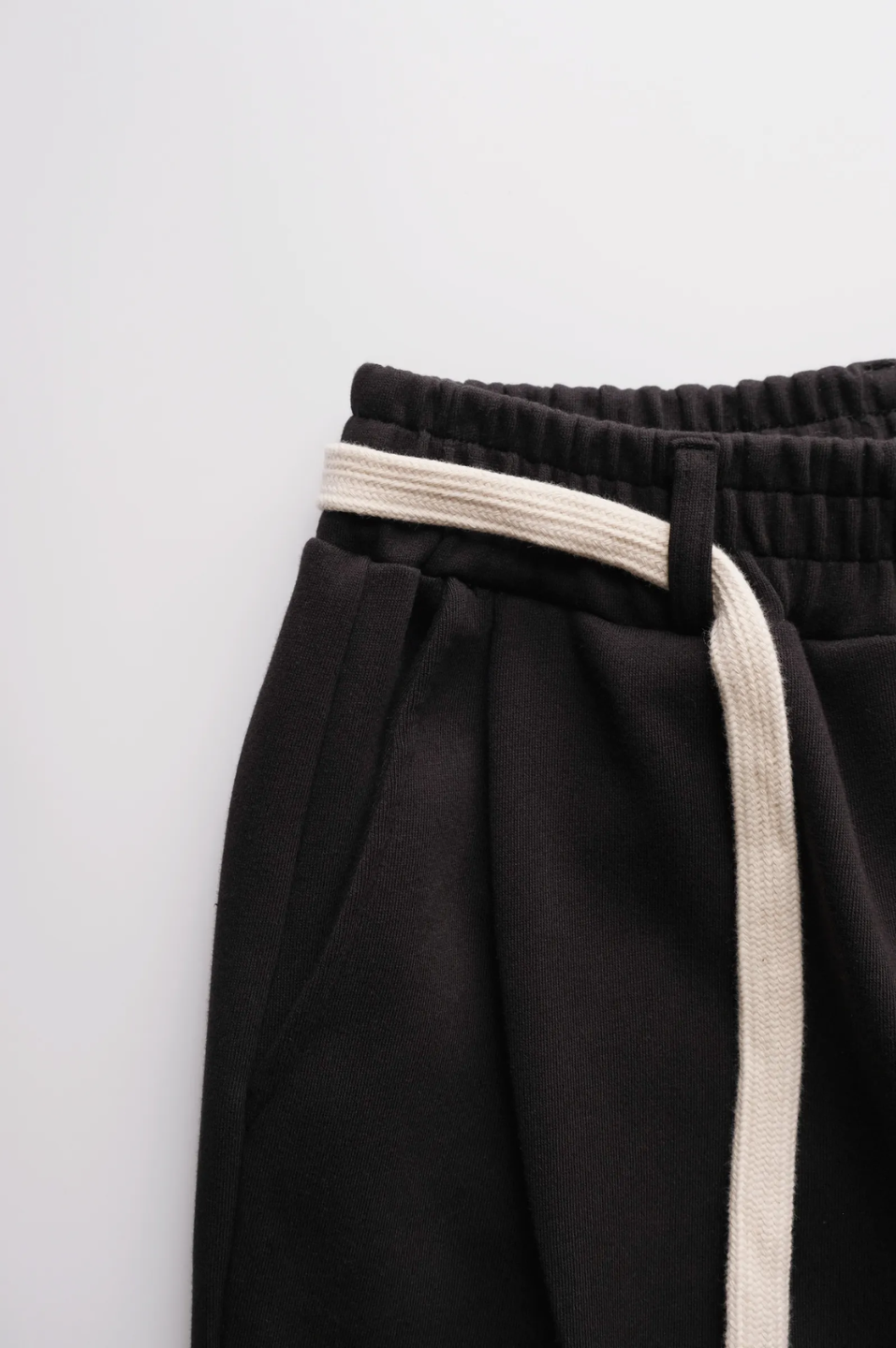 Black pants with a white waistband and side strip on a light gray background