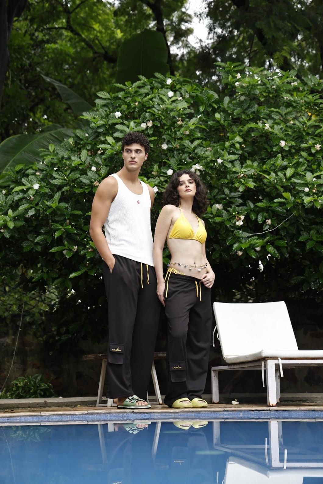 Two people standing by a pool with greenery in the background