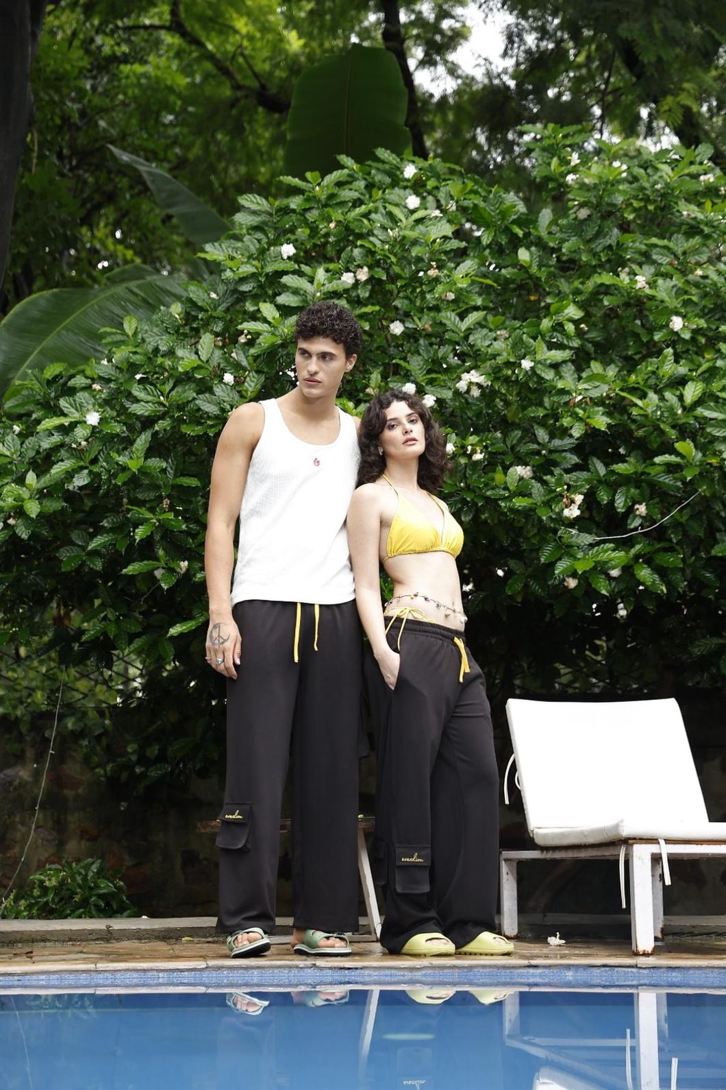 Two people standing by a pool with greenery in the background
