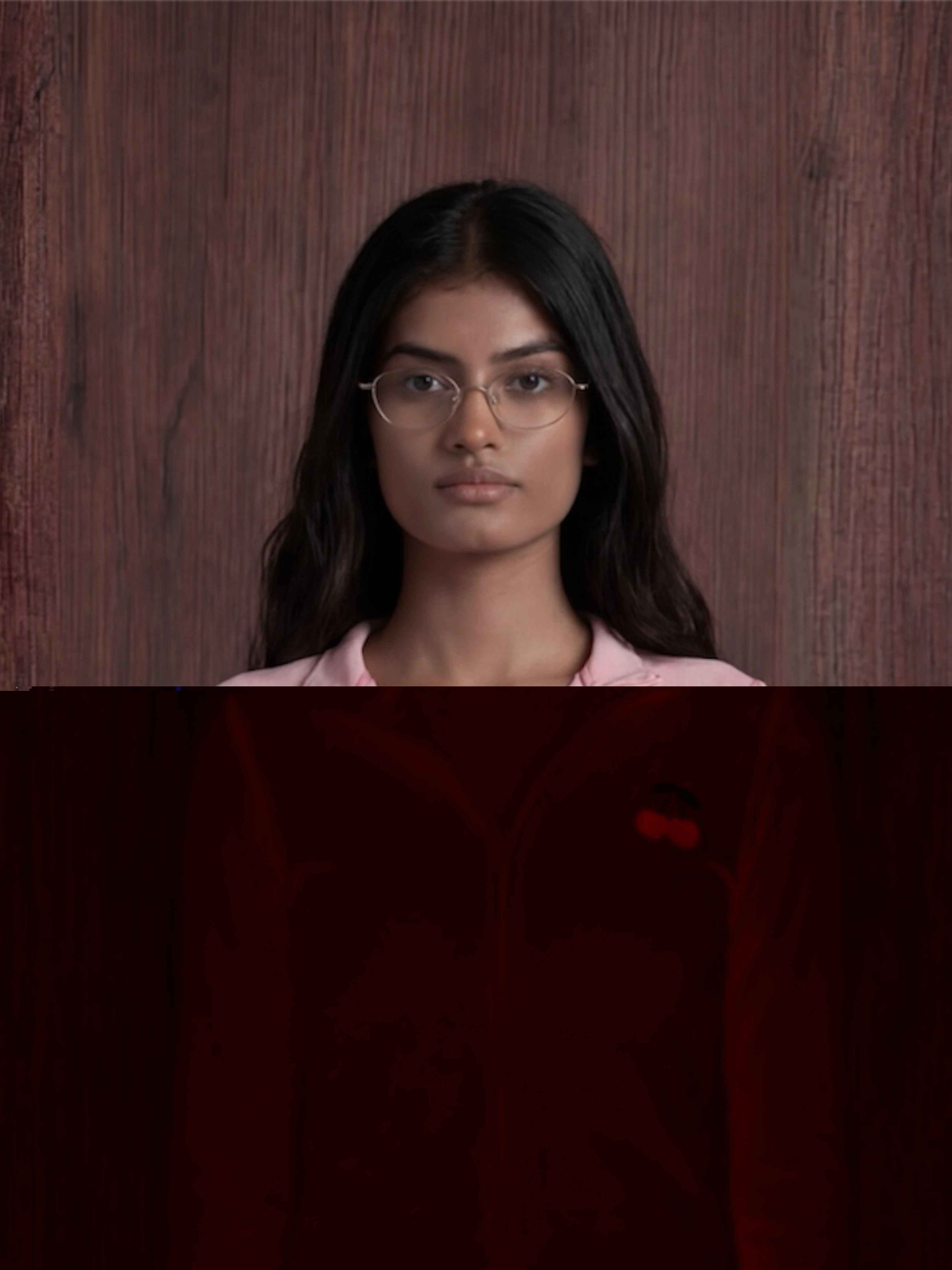 Woman wearing glasses and a pink shirt against a wooden background