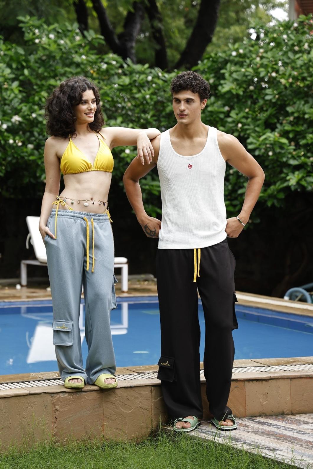 Two people standing by a pool with greenery in the background