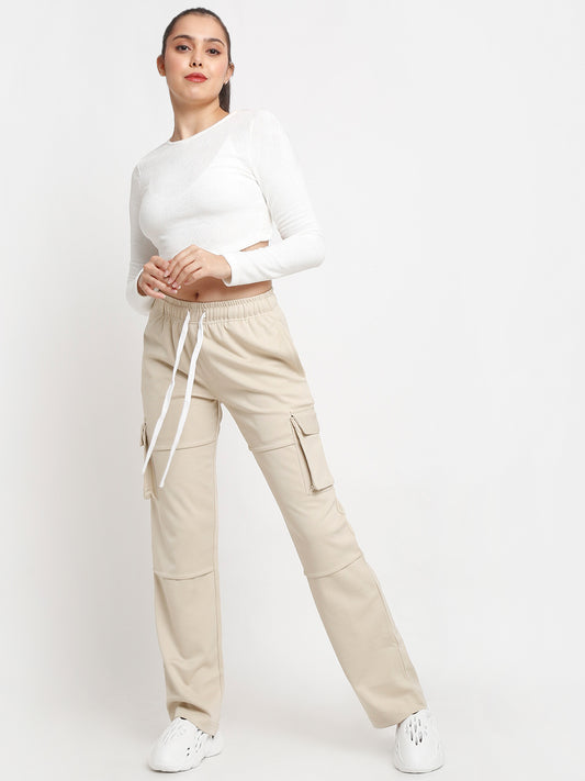 A woman standing and modeling beige utility cargo pants with a white top.