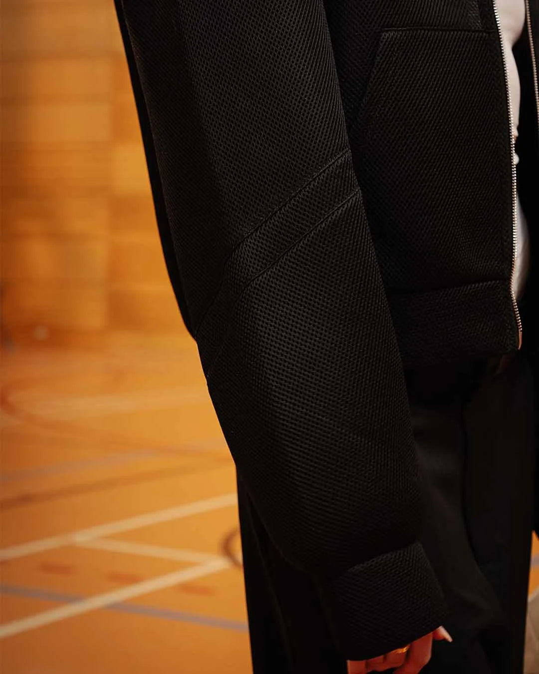 Close-up of a black textured jacket on a wooden floor