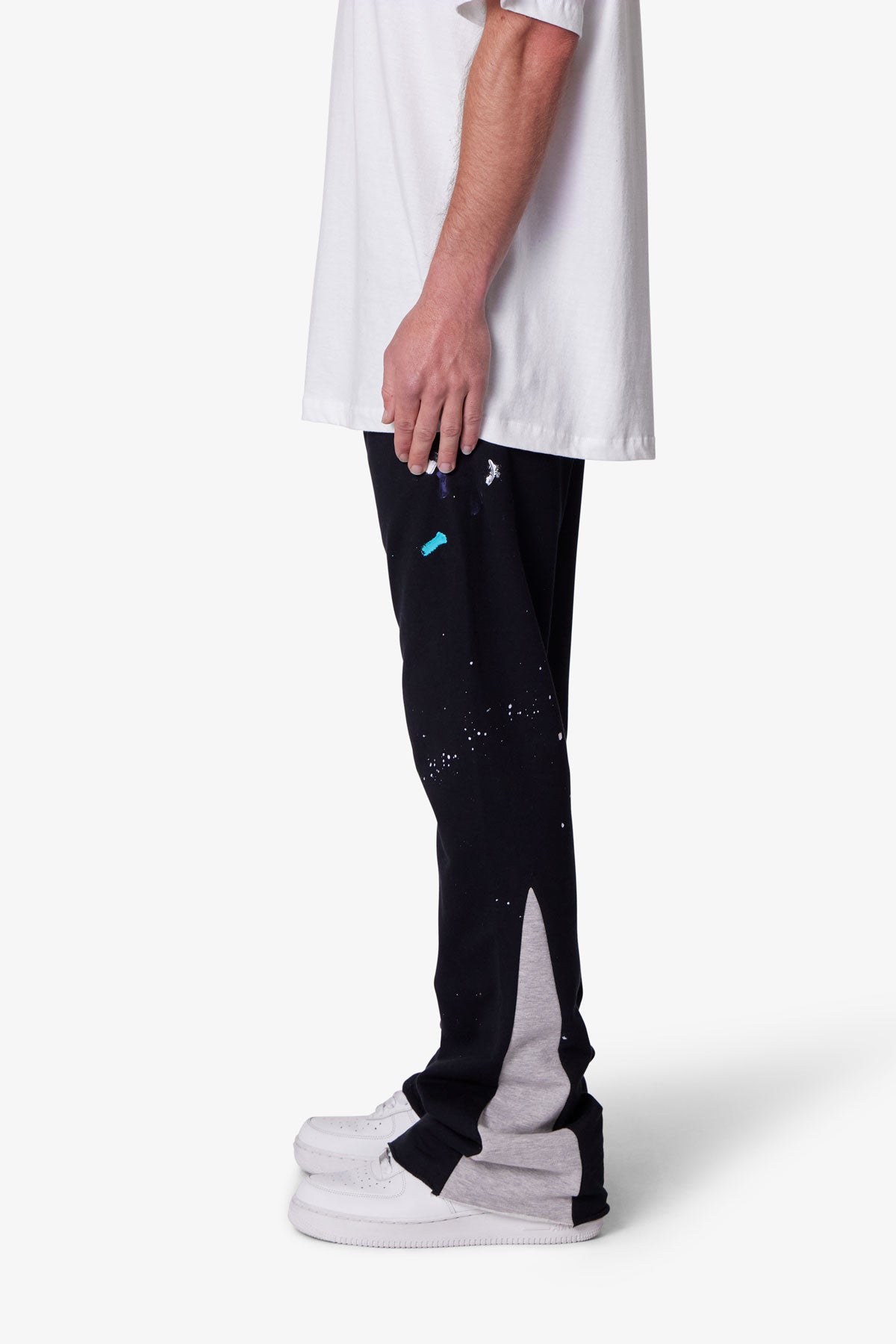 Person wearing black pants with white and grey accents on a white background