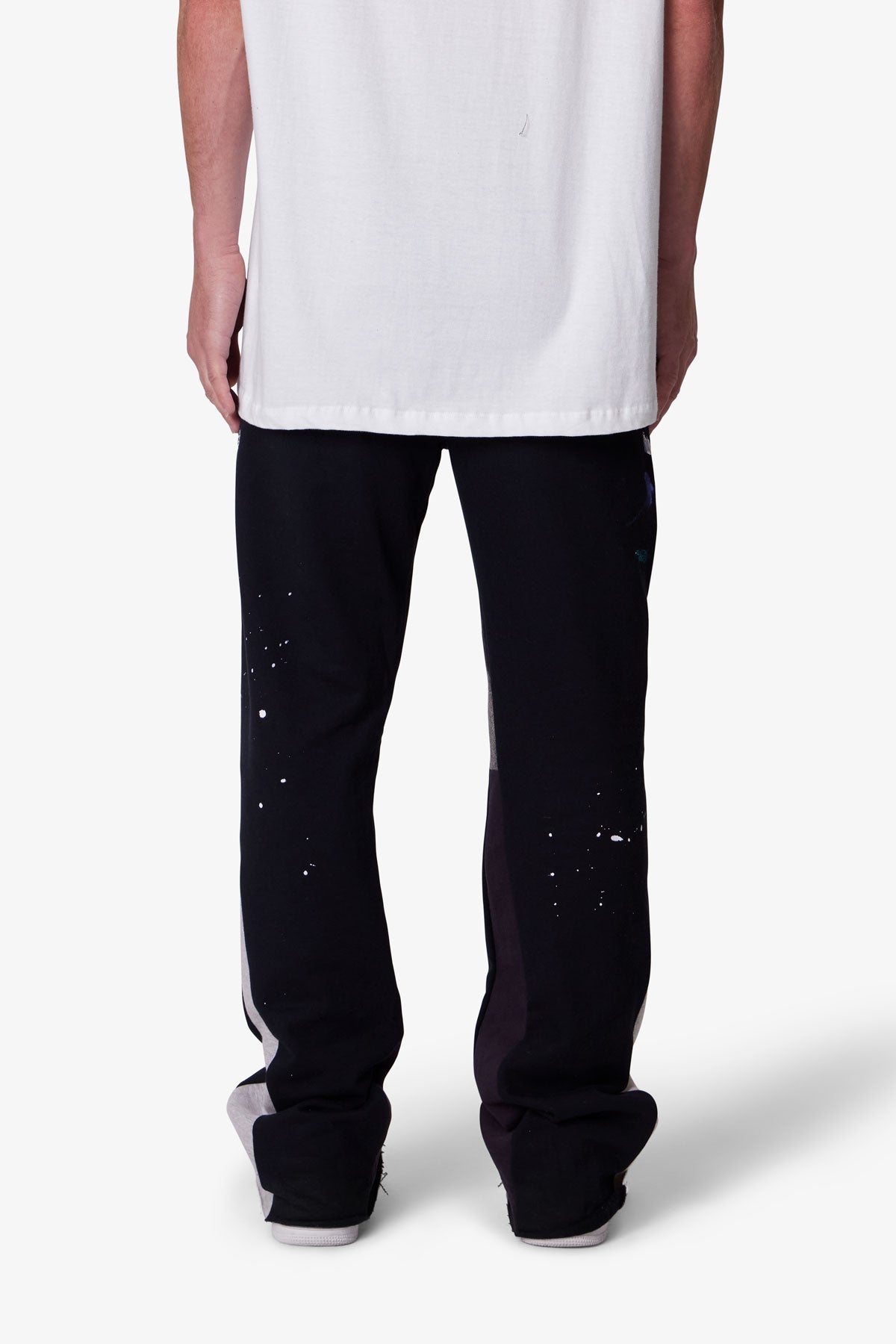 Person wearing black pants with white speckles on a white background
