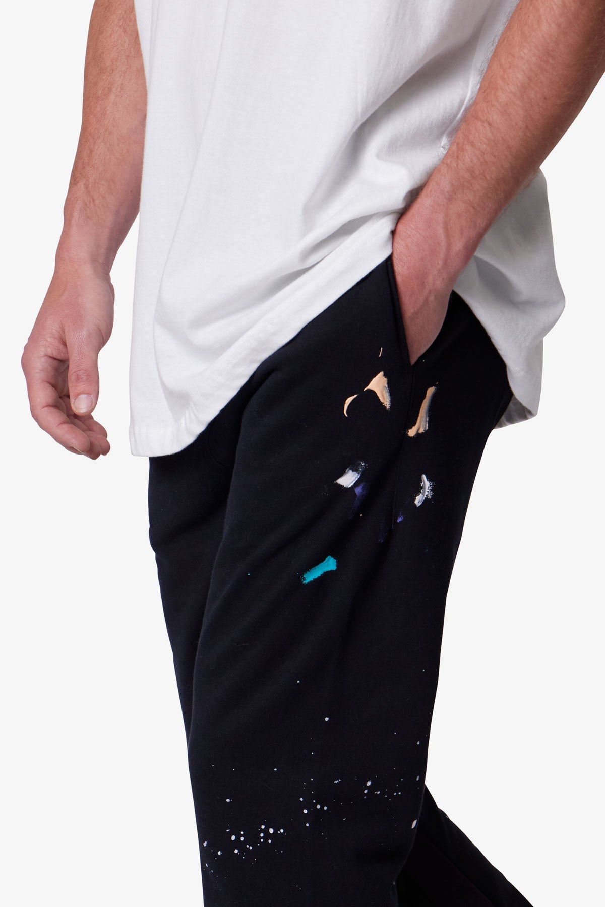 A person wearing black pants with colorful designs on a white background