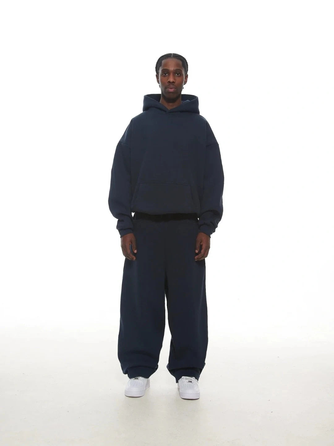 Person wearing a navy blue hoodie and pants set on a white background