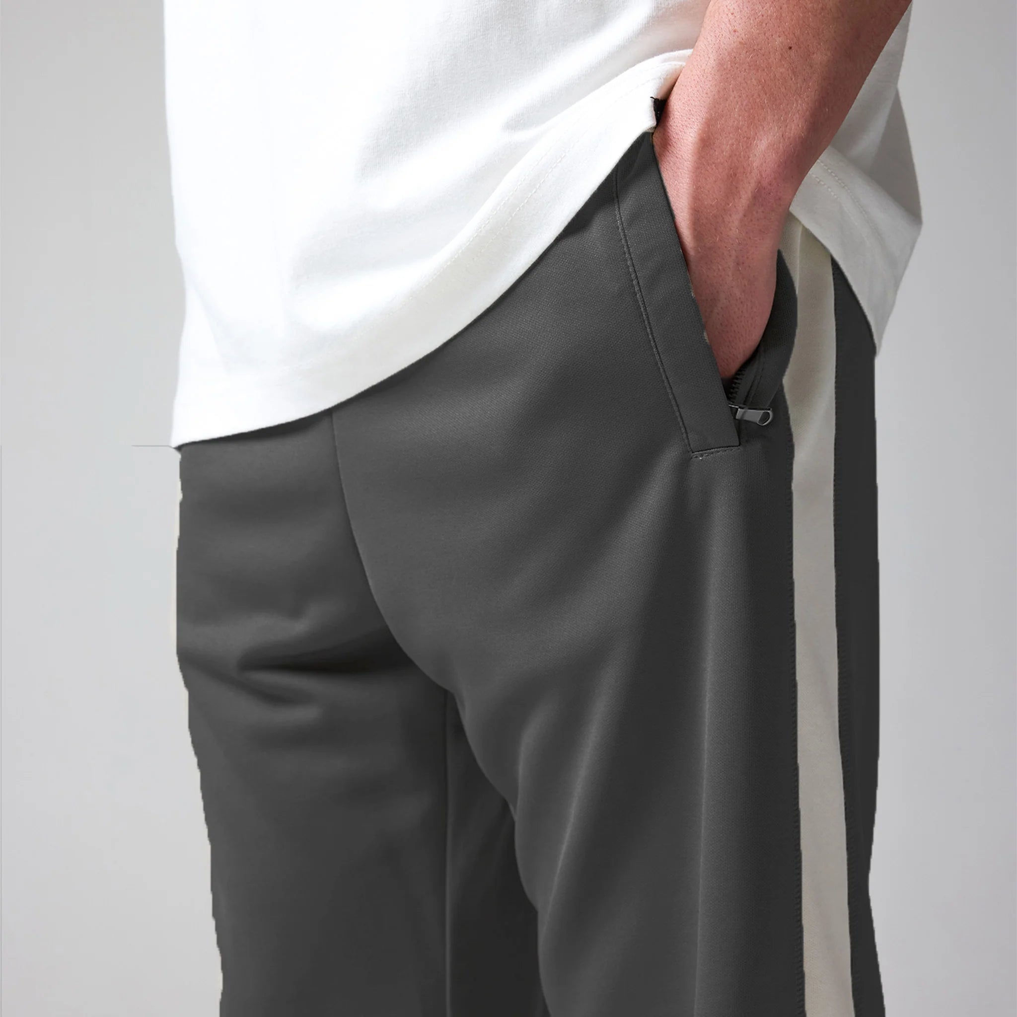 Person wearing grey pants and a white shirt on a light grey background