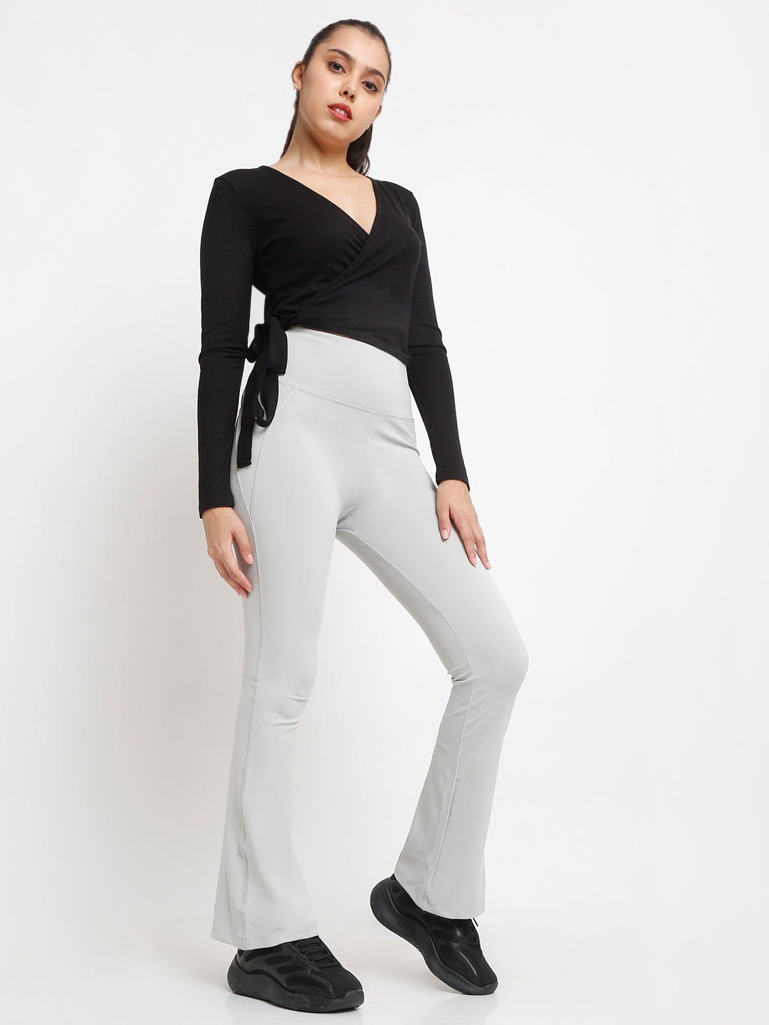 A pair of high-waisted grey flare pants with pockets, in a bootcut style.