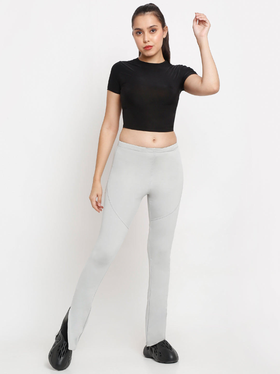 A model wearing grey side slit flare pants and a black sleeveless top, standing against a white background.
