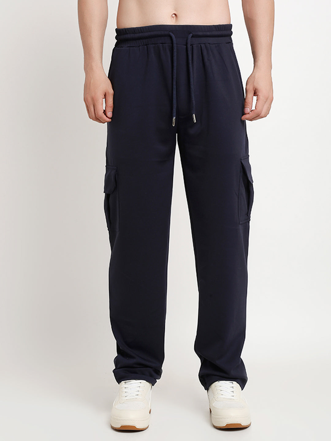 A model wearing navy blue slim fit cargo pants with large side flap pockets, standing against a white background.