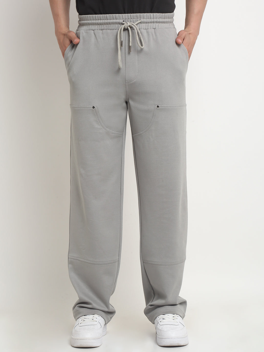 A model wearing gray straight-fit trousers with visible gray rivets and a drawstring waistband.