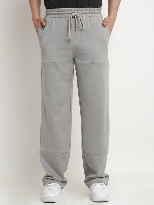 A model wearing gray straight-fit trousers with visible gray rivets and a drawstring waistband.