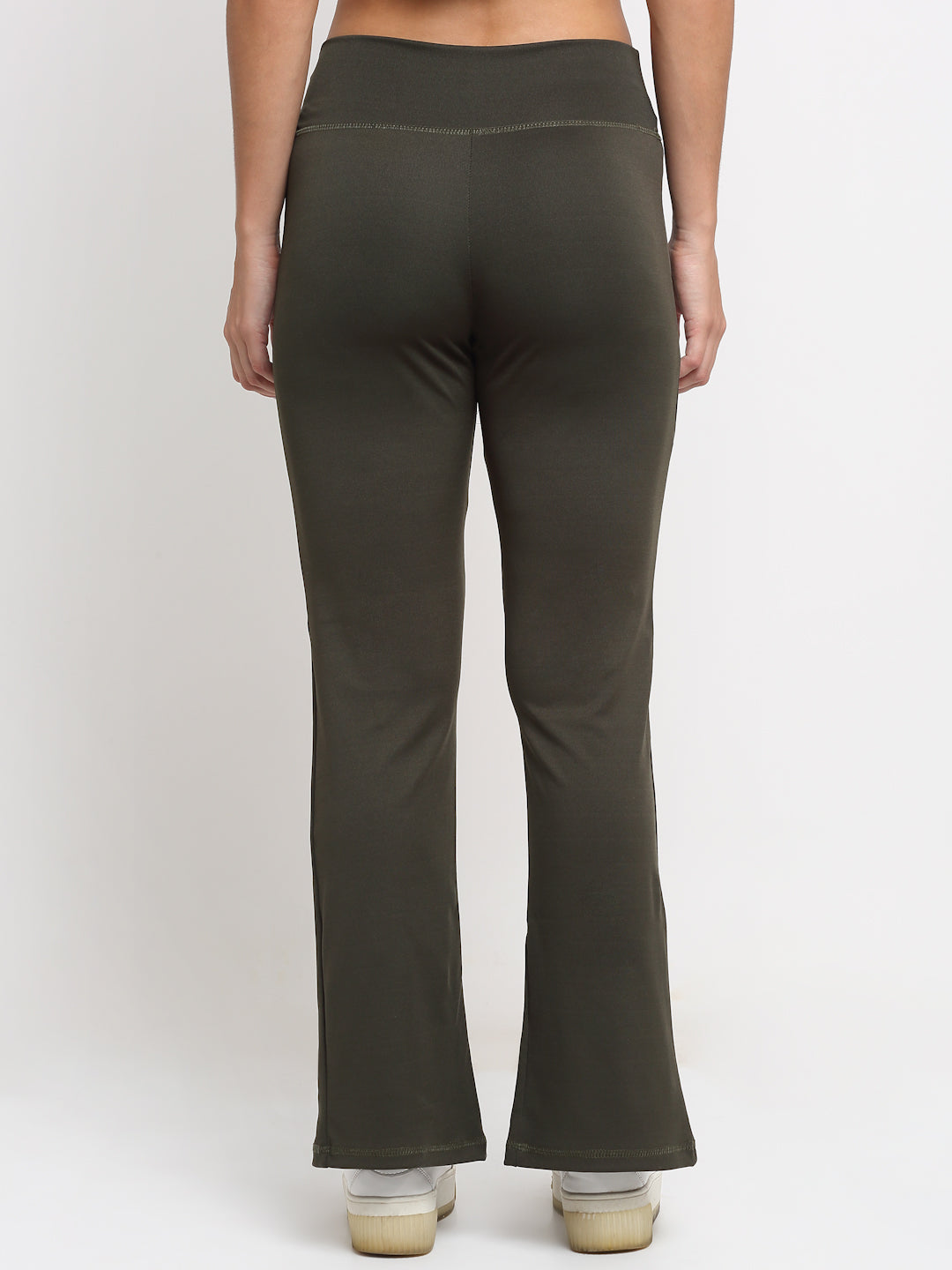 A pair of high waist green yoga pants with front slits and a flared leg design, being modeled by a person wearing white sneakers.