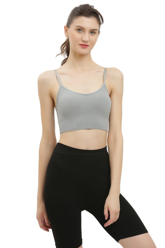 A woman wearing a grey seamless padded sports bra with spaghetti straps and a racerback style, paired with black shorts.