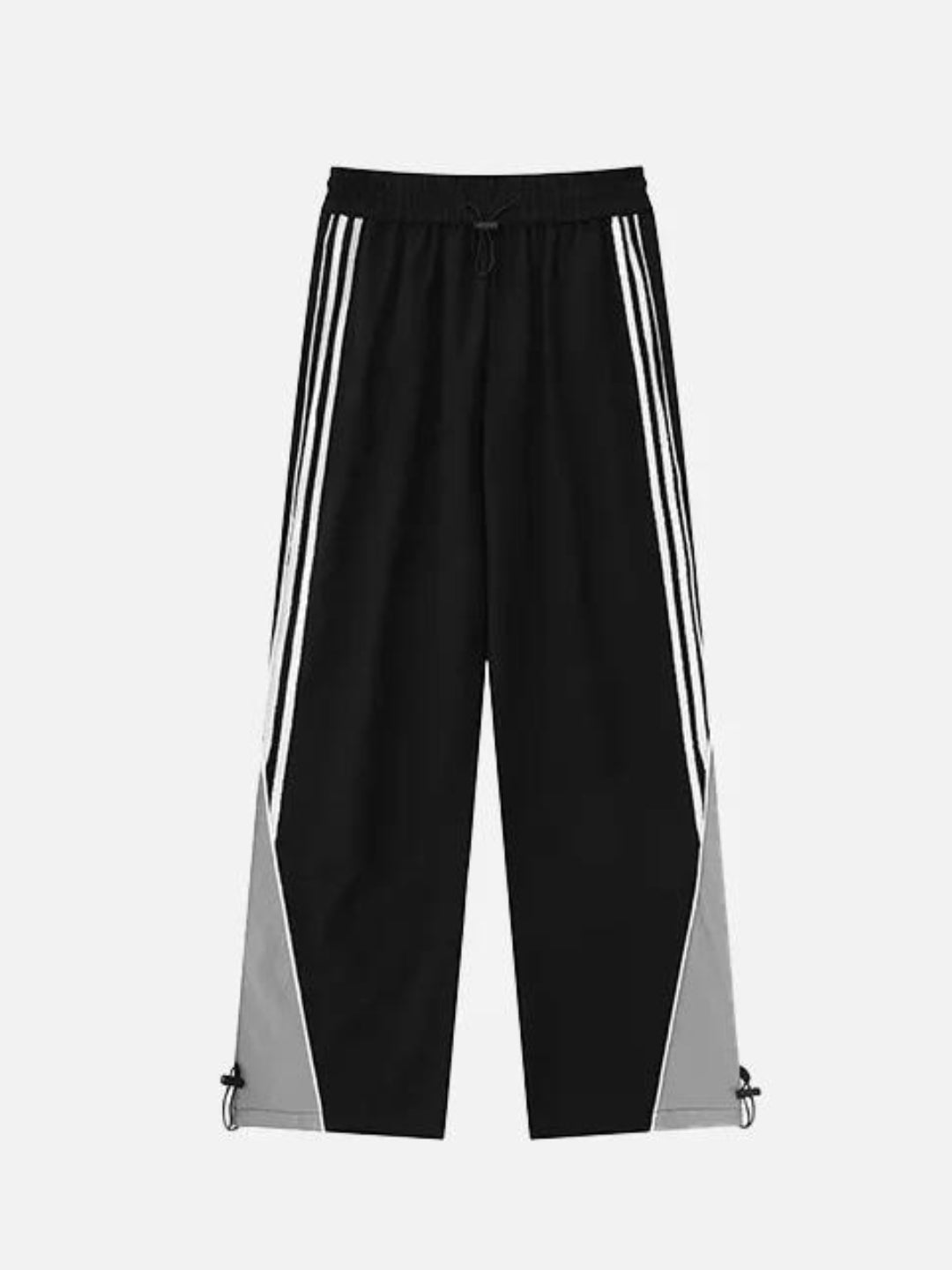 A person standing side-on, wearing striped parachute pants with contrast piping and an elasticated waistband with adjustable drawstrings.