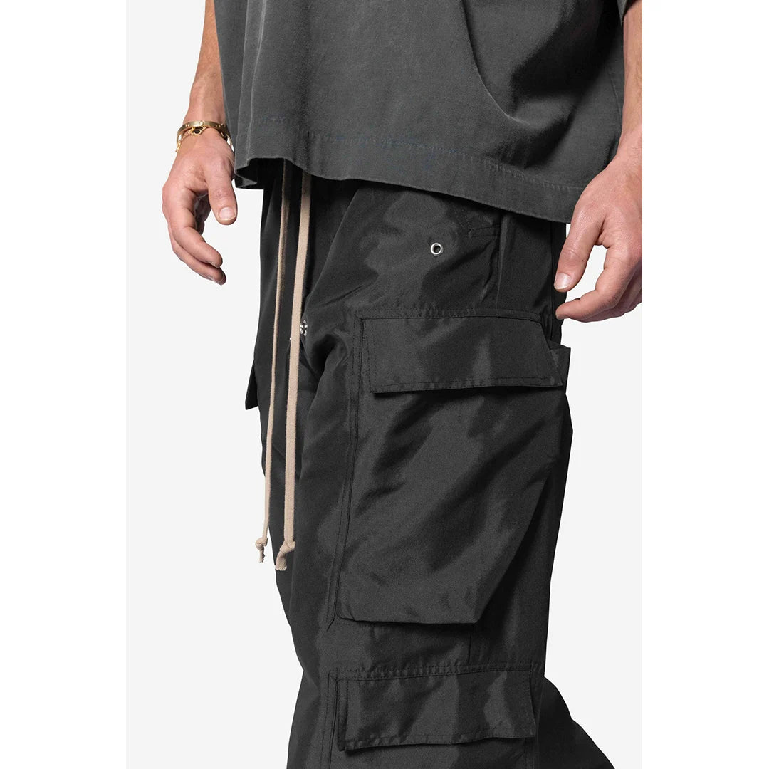 Person wearing black cargo shorts with a plain white background