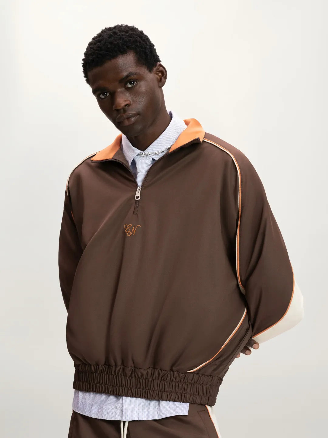 Man wearing a brown jacket with orange accents on a white background