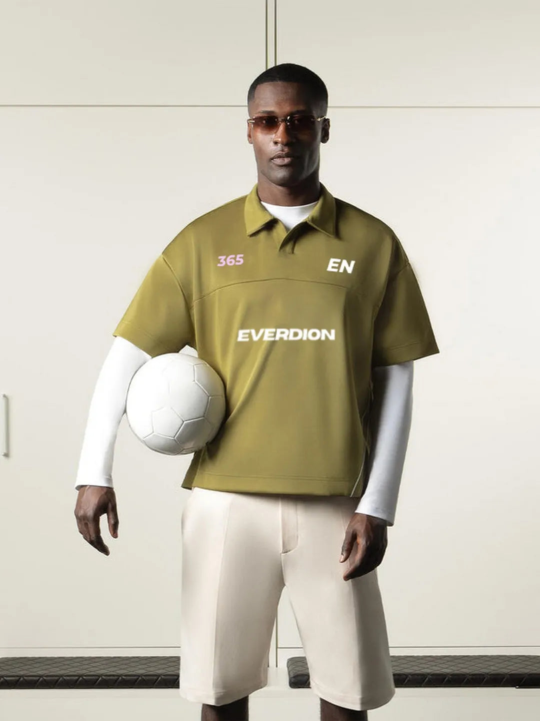Person wearing a green sports jersey with 'EVERDION' branding, holding a soccer ball.