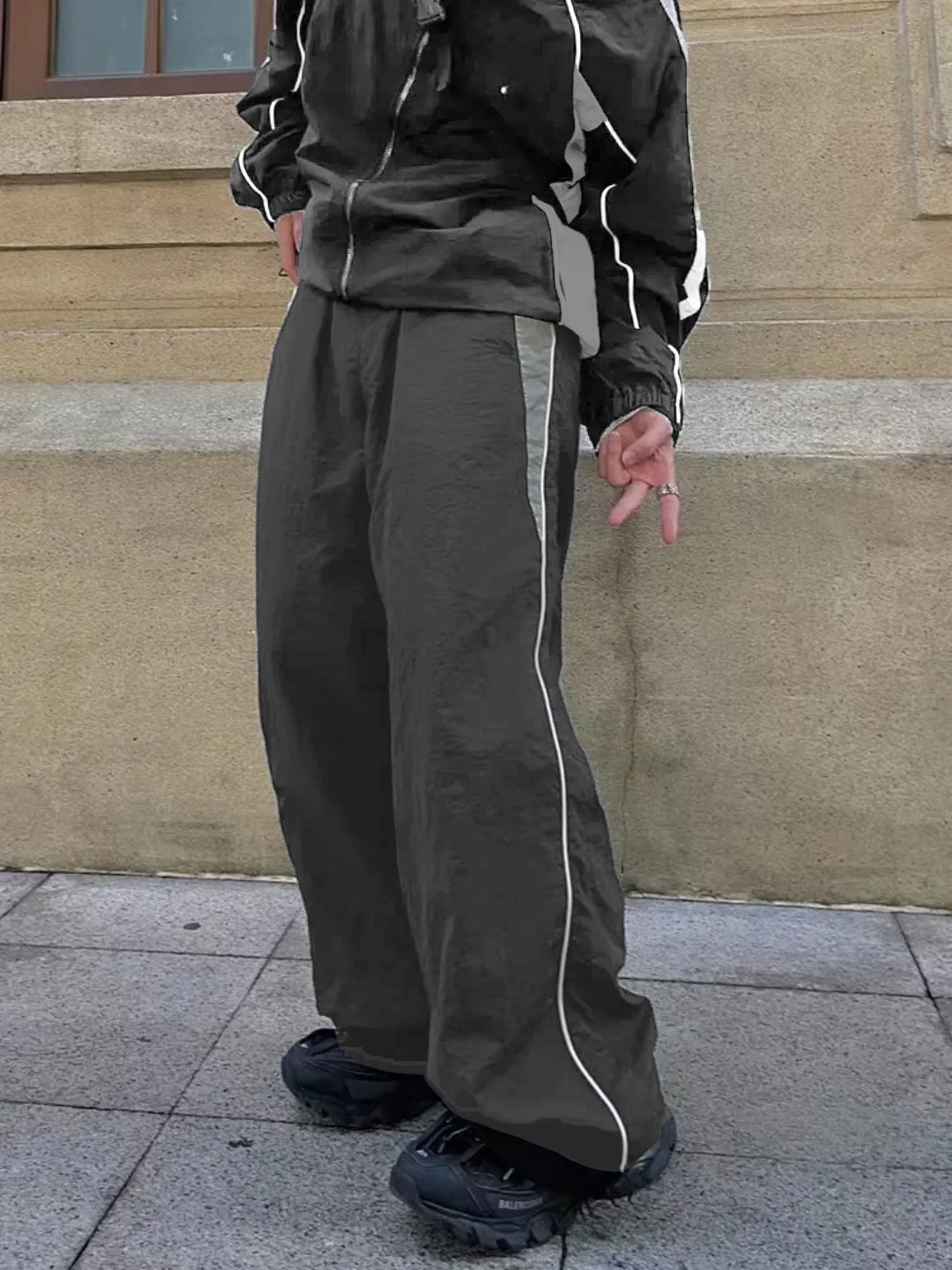 dark grey trackpants with contrast white piping and an elasticated waistband with drawstrings.