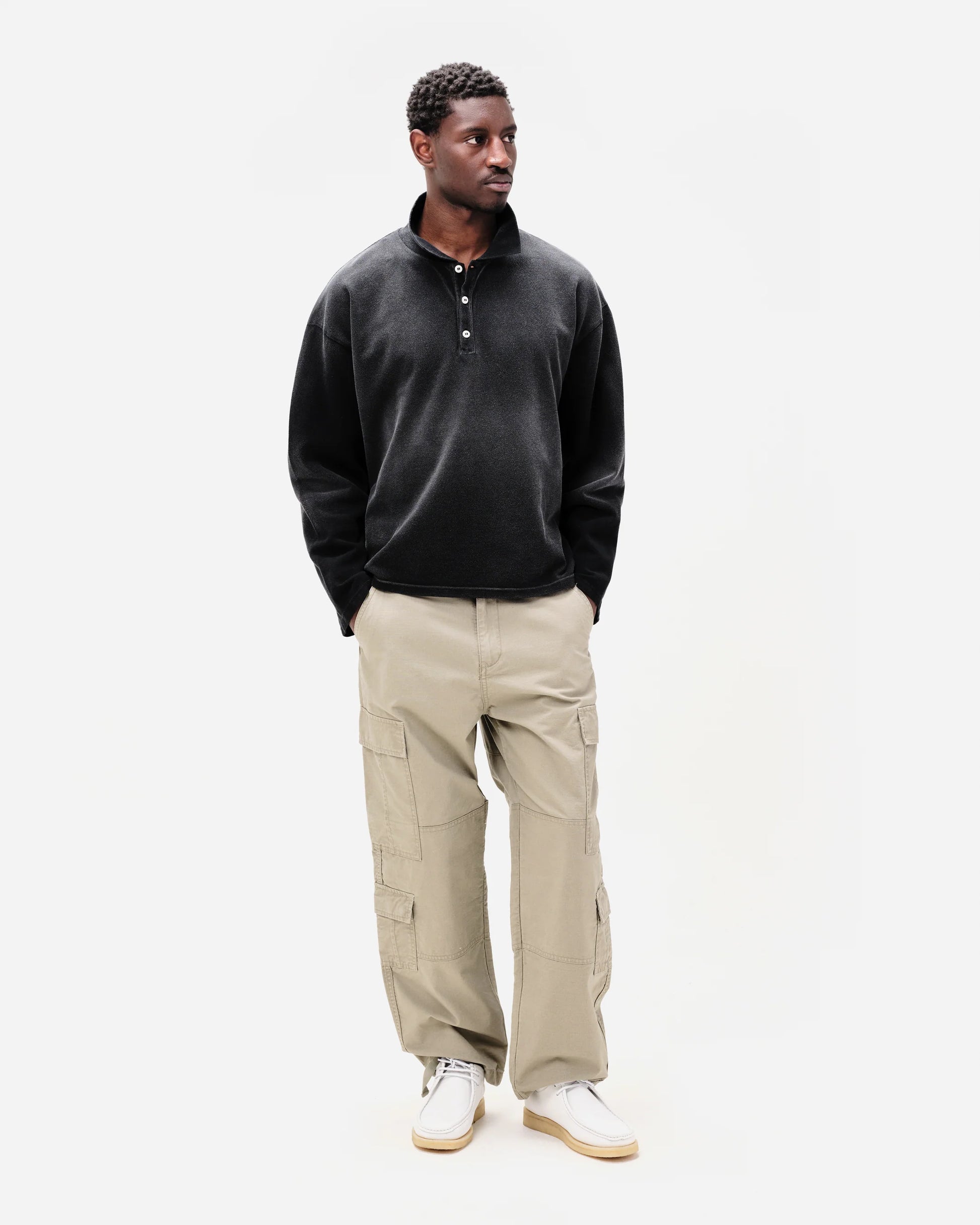 Man wearing a black pullover and beige cargo pants on a white background