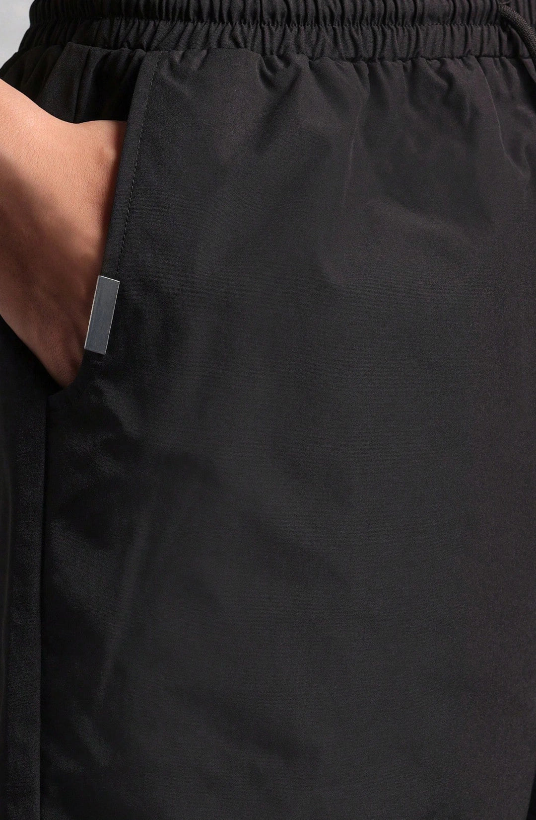Close-up of black pants with a small tag on a plain background