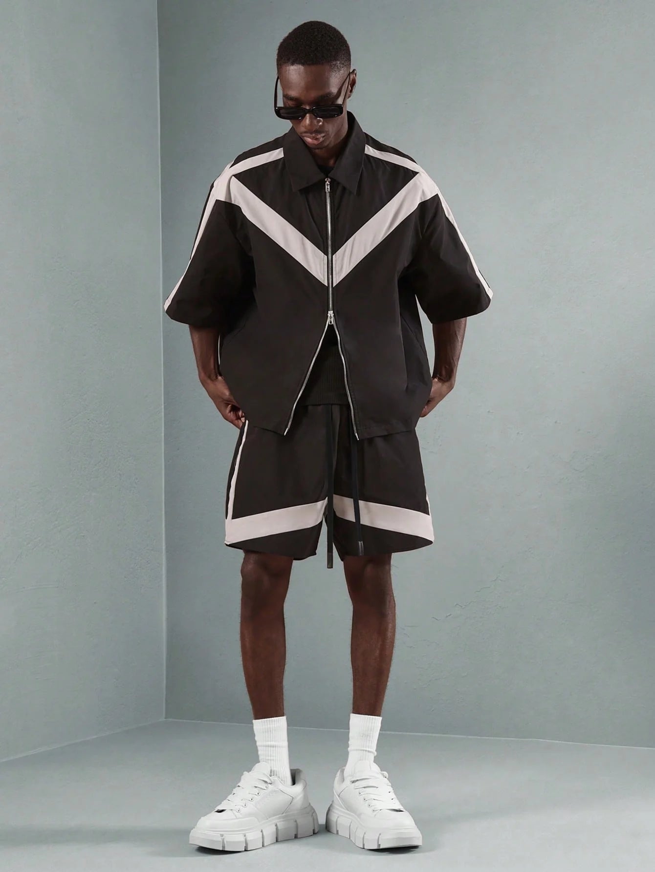 Person wearing a black and white outfit with a grey background