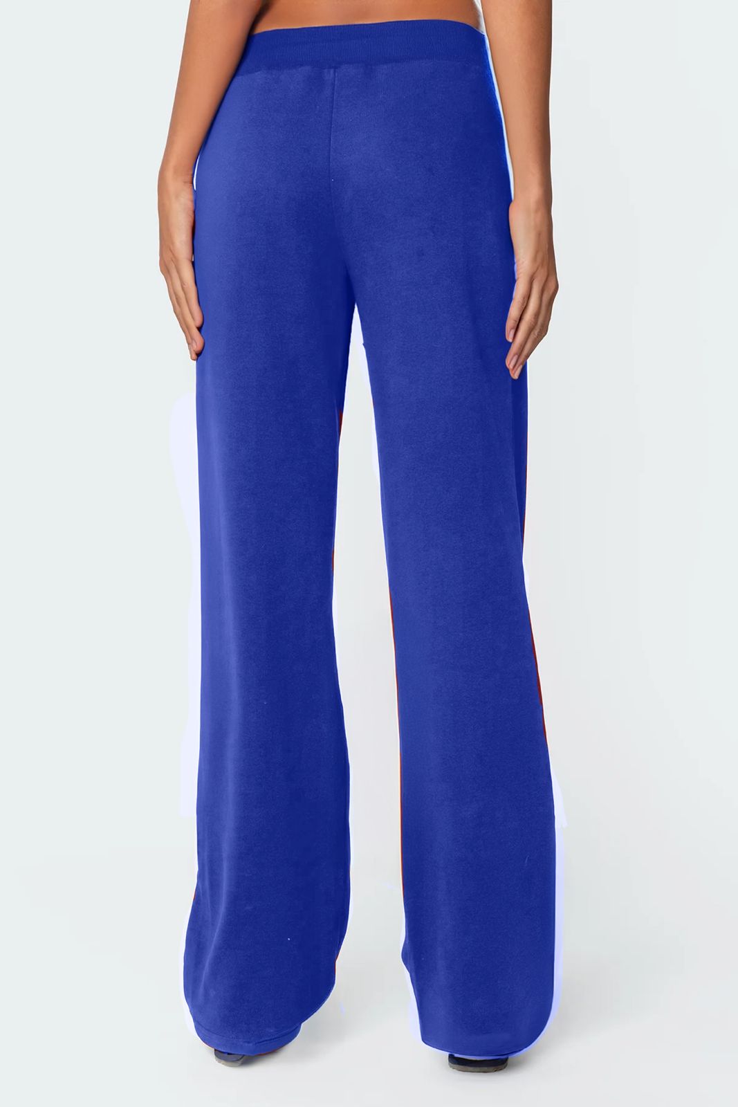 A female model wearing a white tank top and blue lowrise trackpants with the number '06' printed on the left leg.