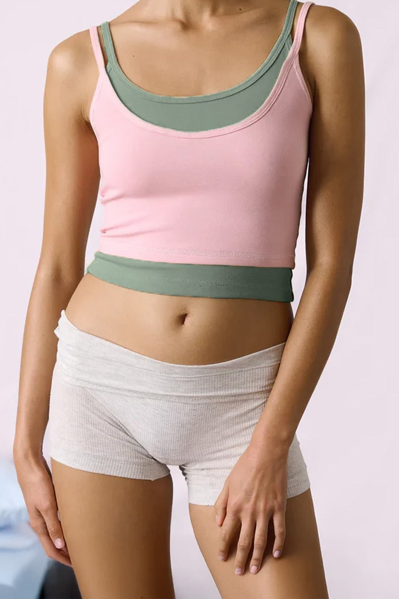 Person wearing a pink and green sports bra and white shorts on a light background