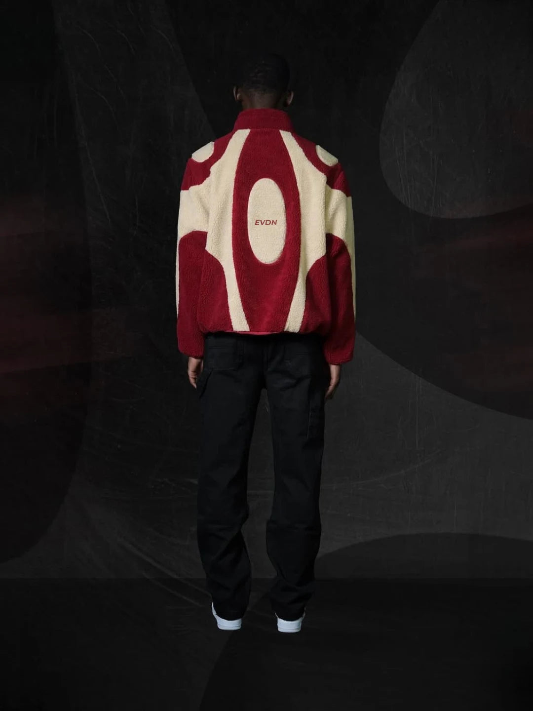 Person wearing a red and white patterned jacket with 'EVDN' branding on a dark background