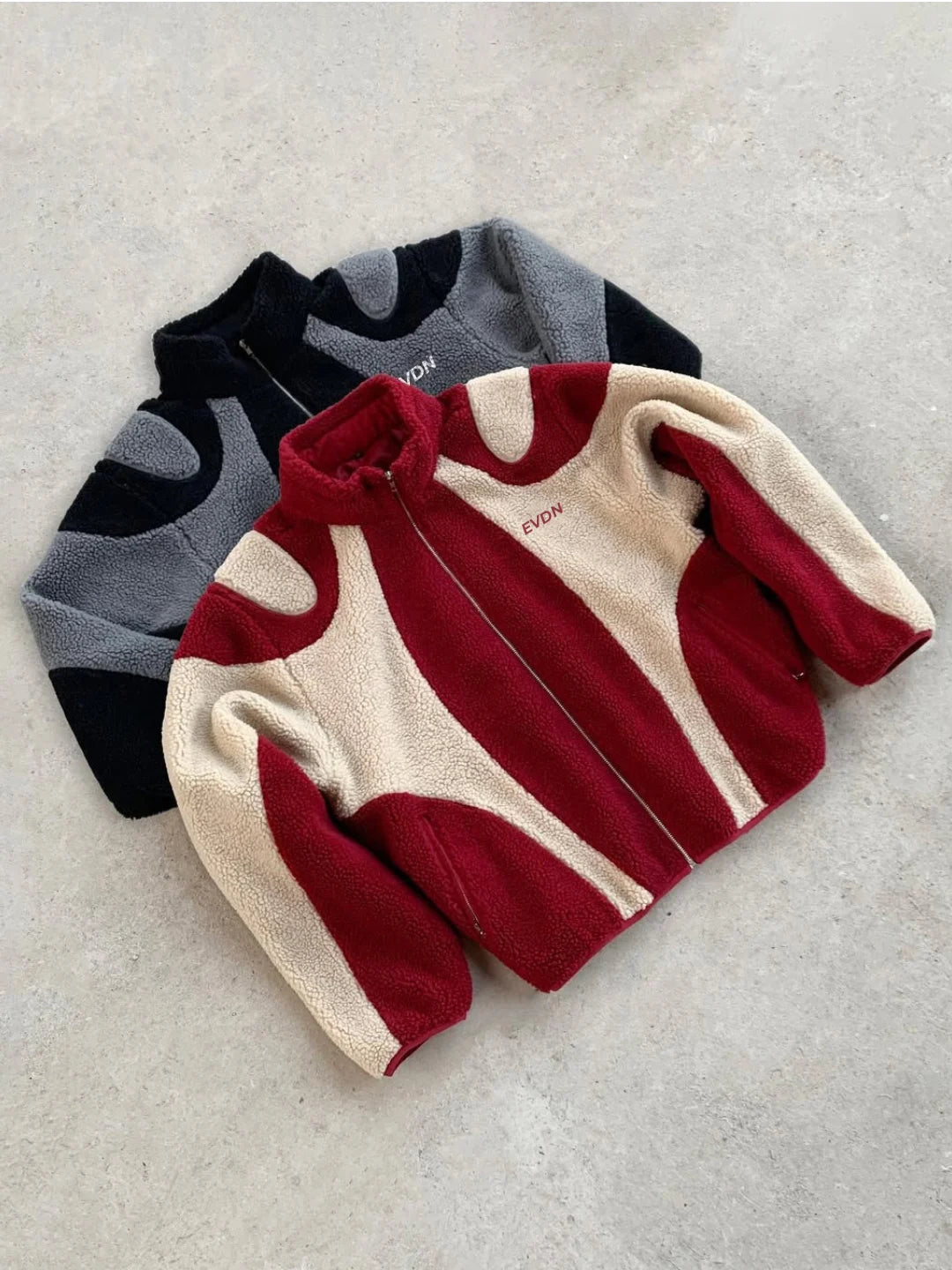 Three children's sweaters in black, red, and beige on a light gray background
