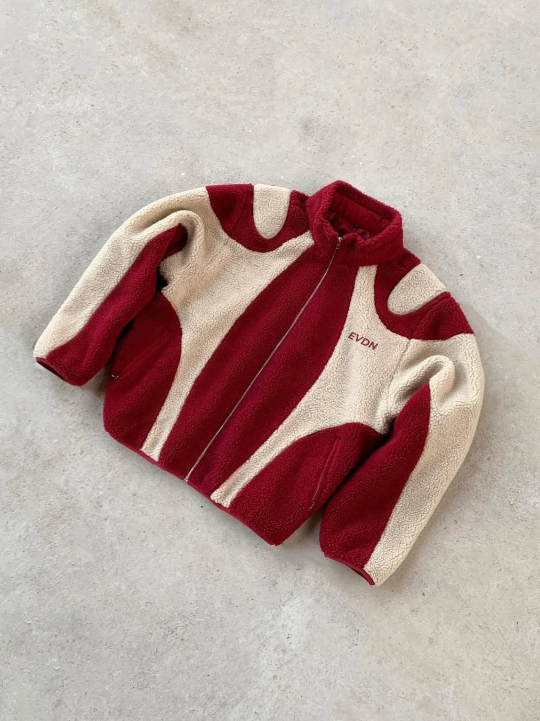 Red and beige fleece jacket with 'EVDN' branding on a light gray background