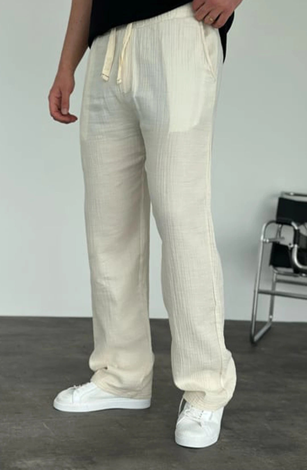 Person wearing beige pants and white sneakers in a minimal indoor setting