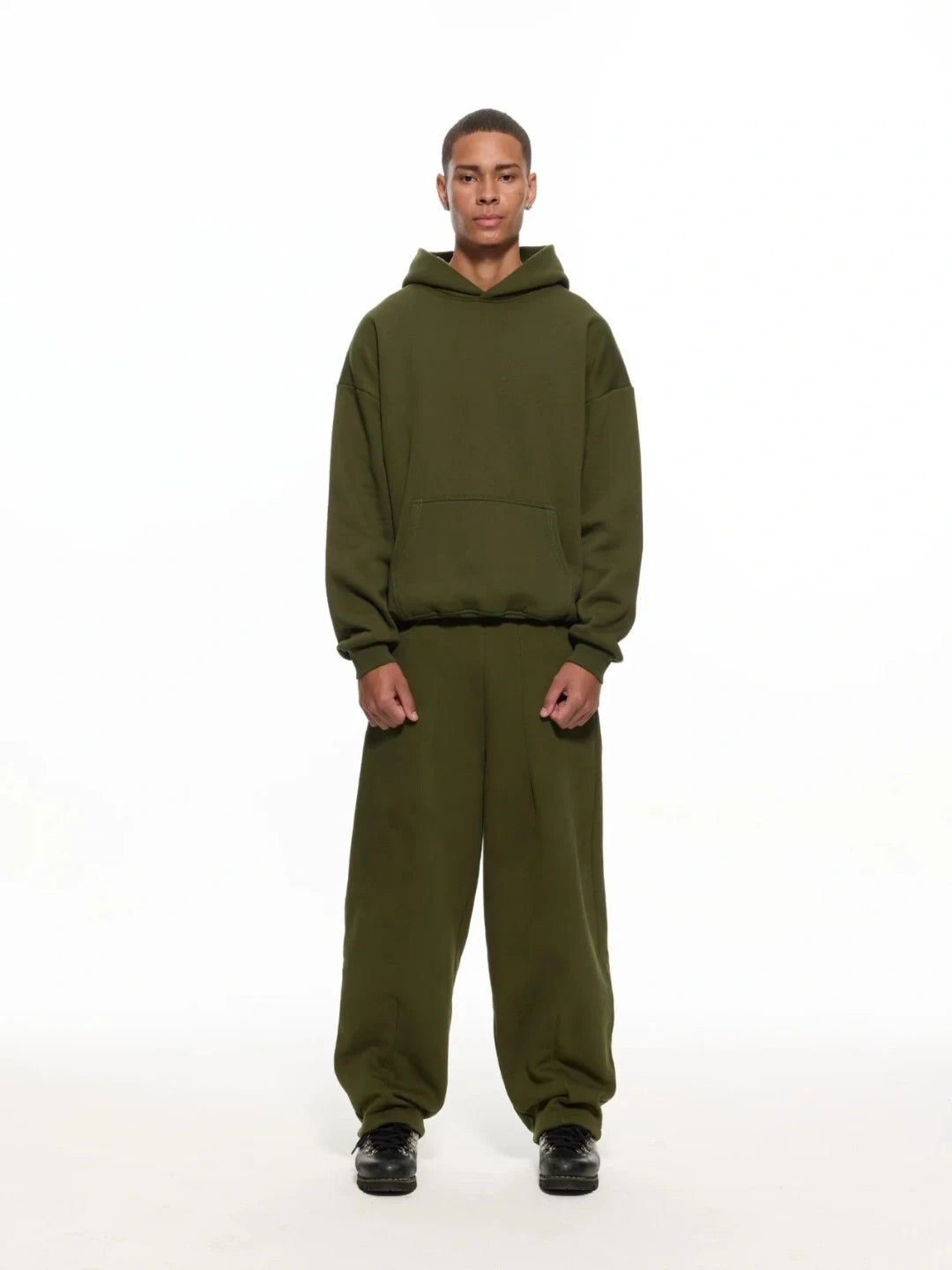 Person wearing a green hoodie and pants on a white background
