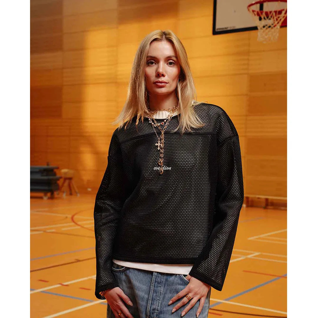 Person wearing a black mesh sweater in an indoor basketball court