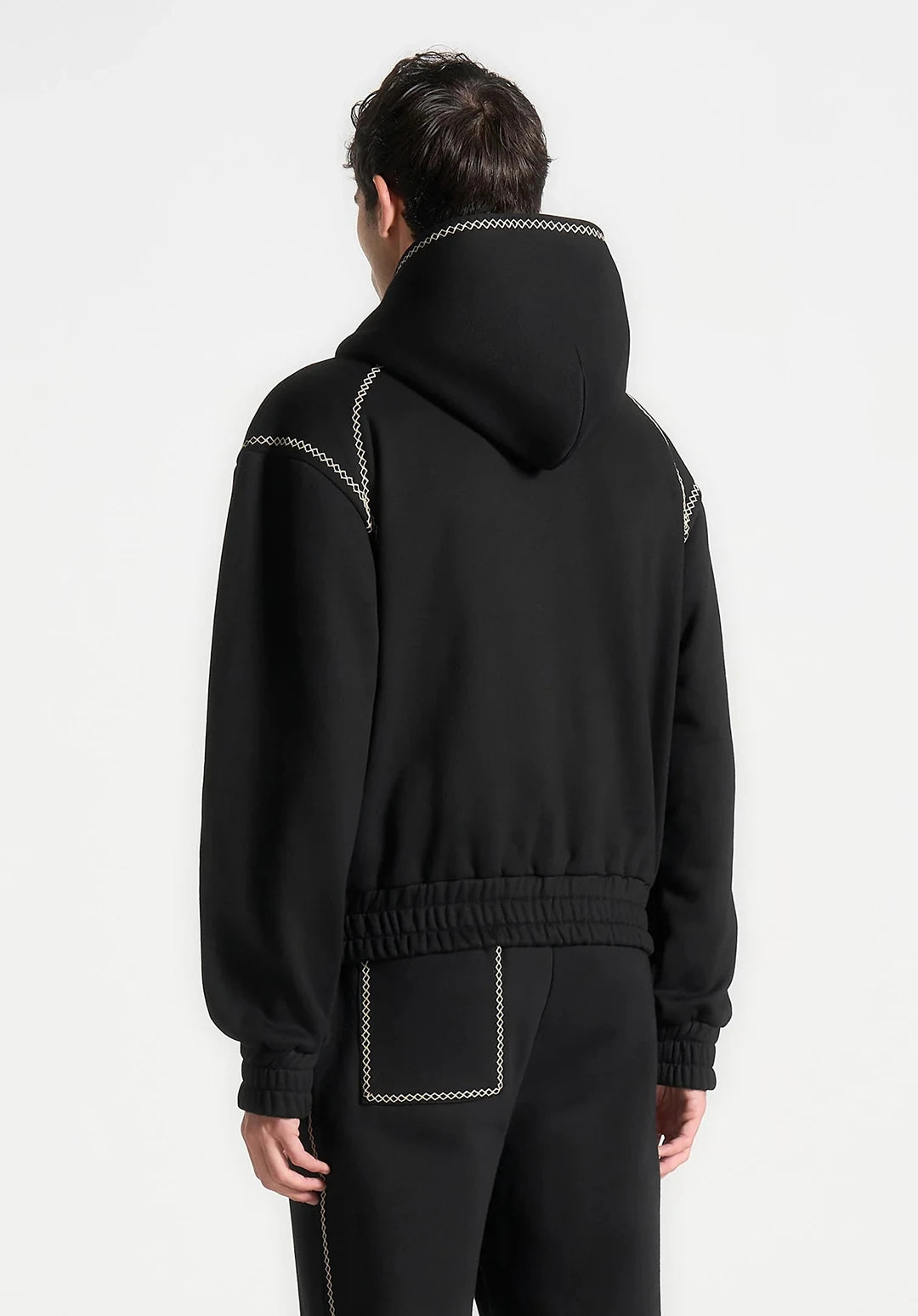 Person wearing a black hoodie with white stitching on a white background