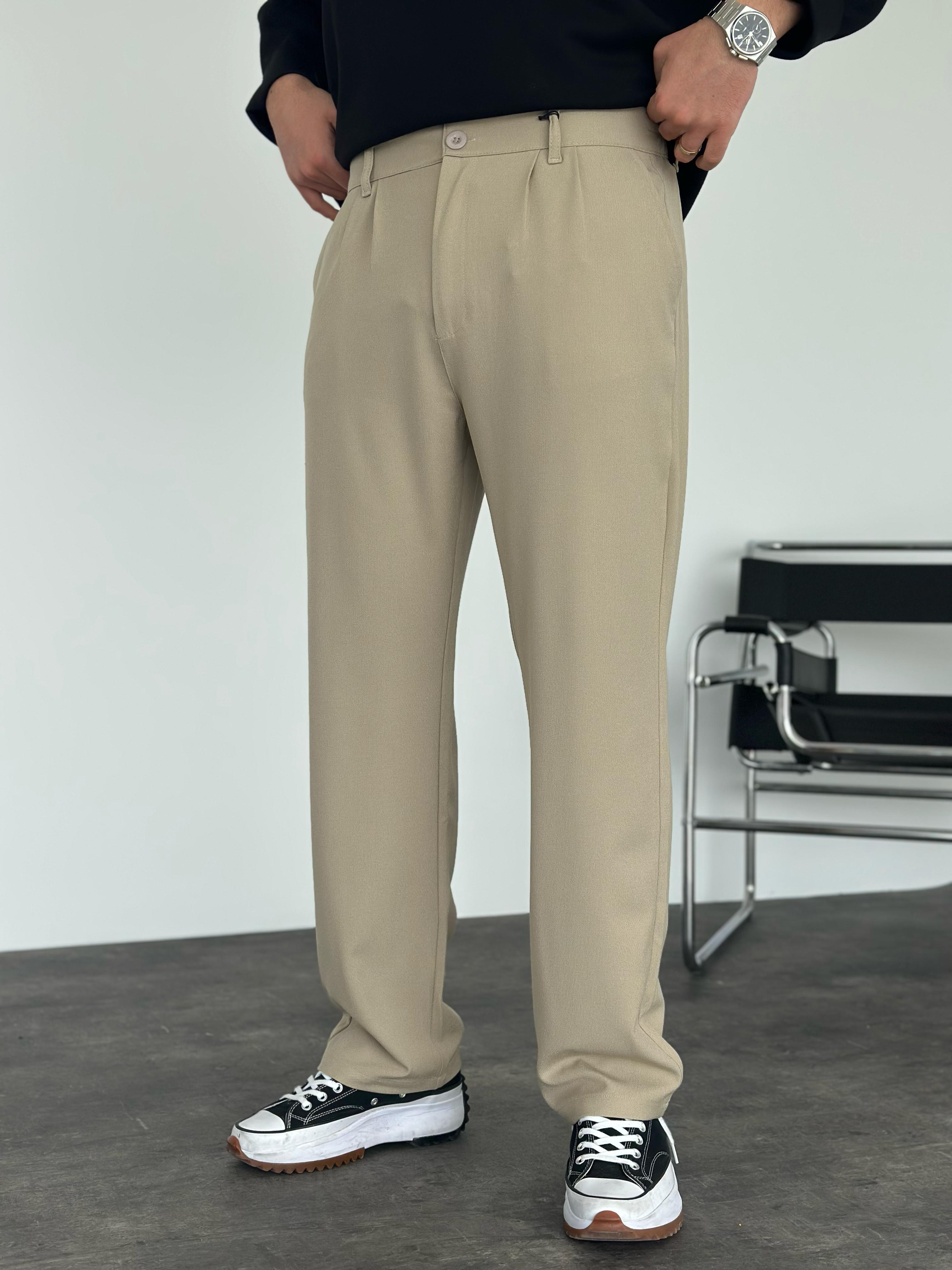 Person wearing beige pants with a plain background