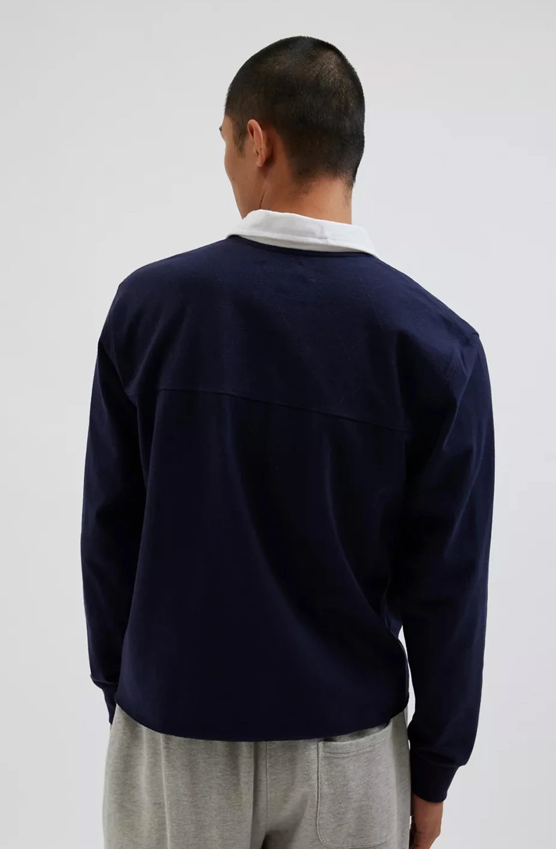 Person wearing a navy blue sweater over a white shirt on a plain background