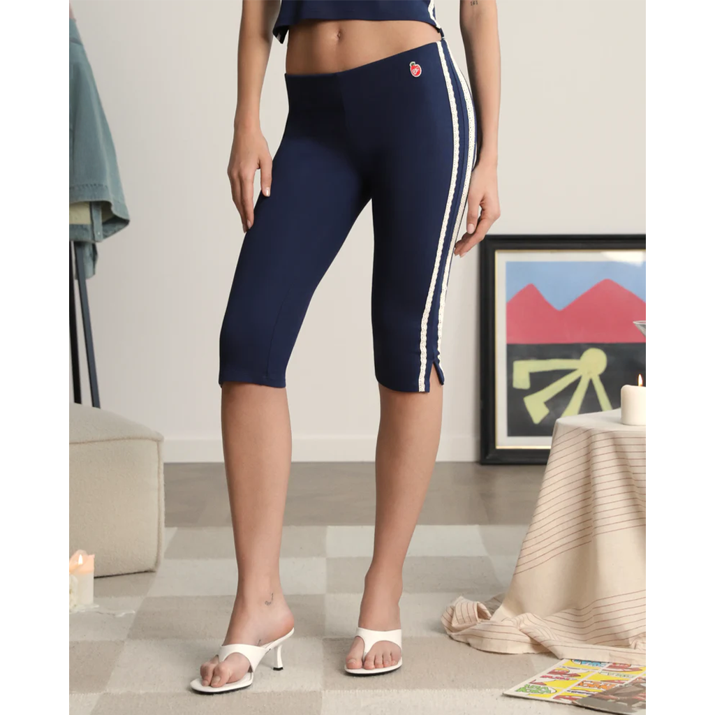 A person wearing navy blue leggings with white stripes in a room setting.