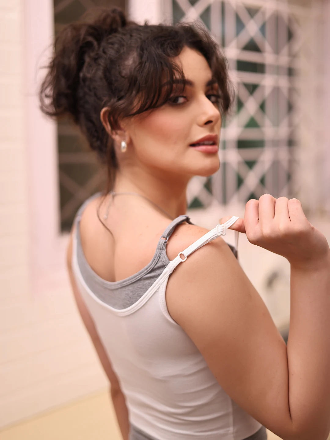 Woman wearing a gray tank top with a blurred background