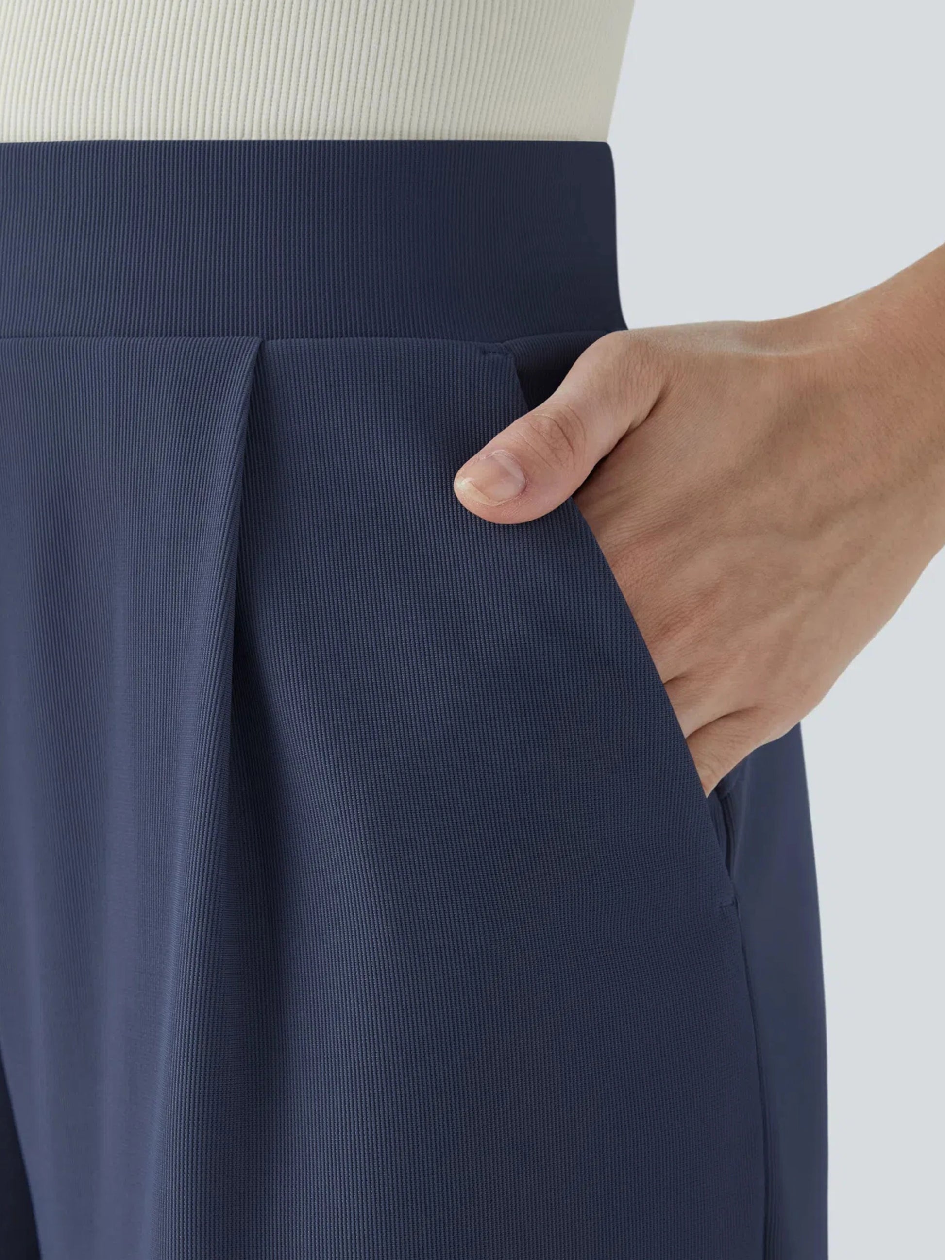 Navy blue skirt with a hand touching the fabric on a light background