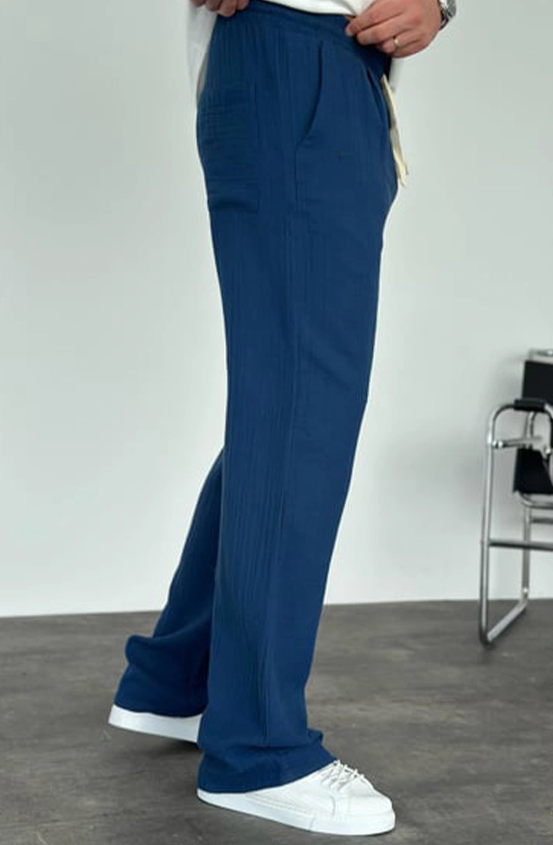 Person wearing blue pants and white shoes on a plain background