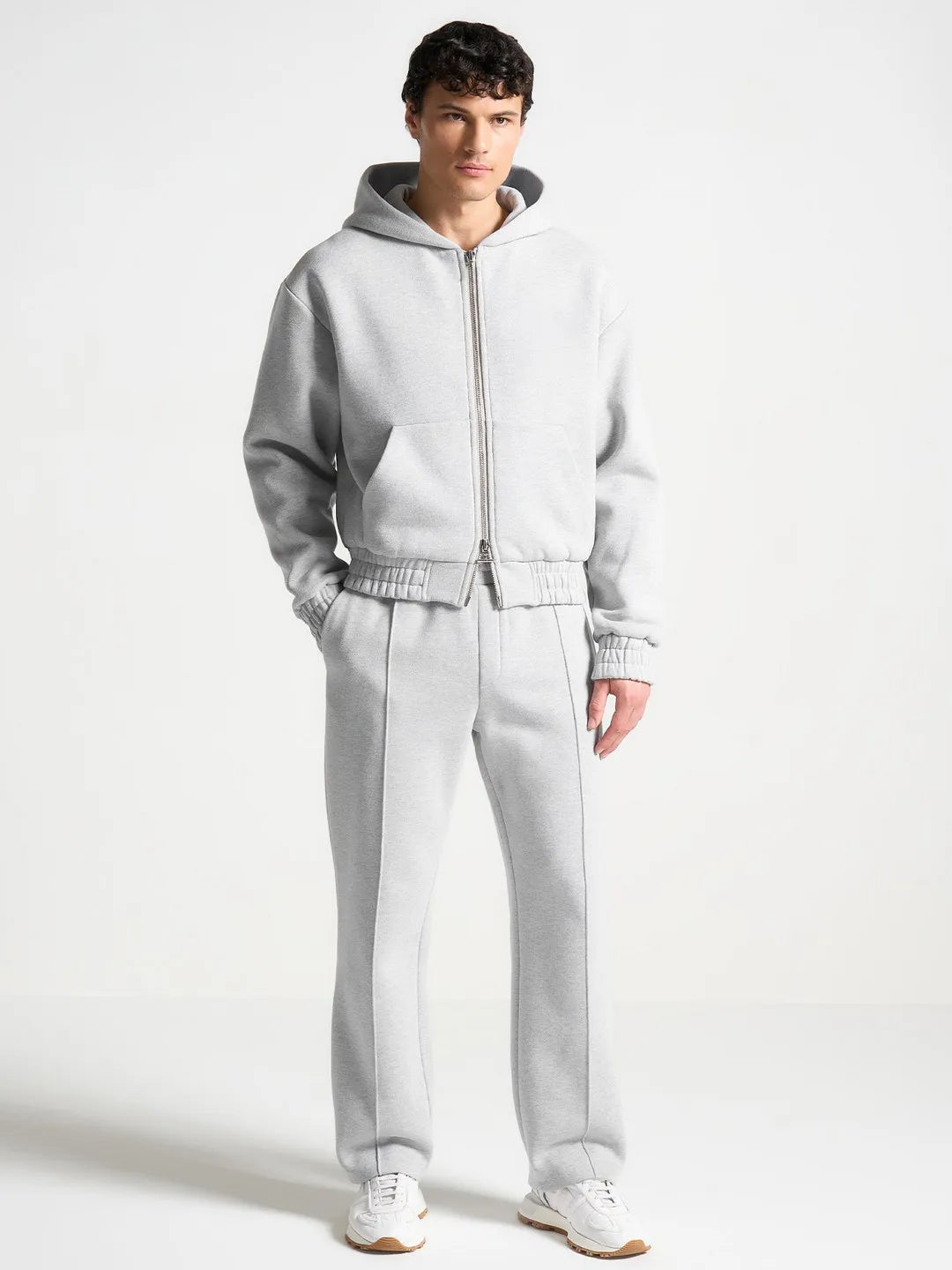 Person wearing a light gray tracksuit on a white background