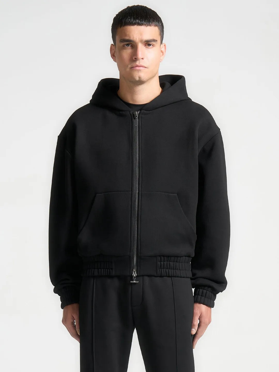 Man wearing a black hoodie and pants on a white background