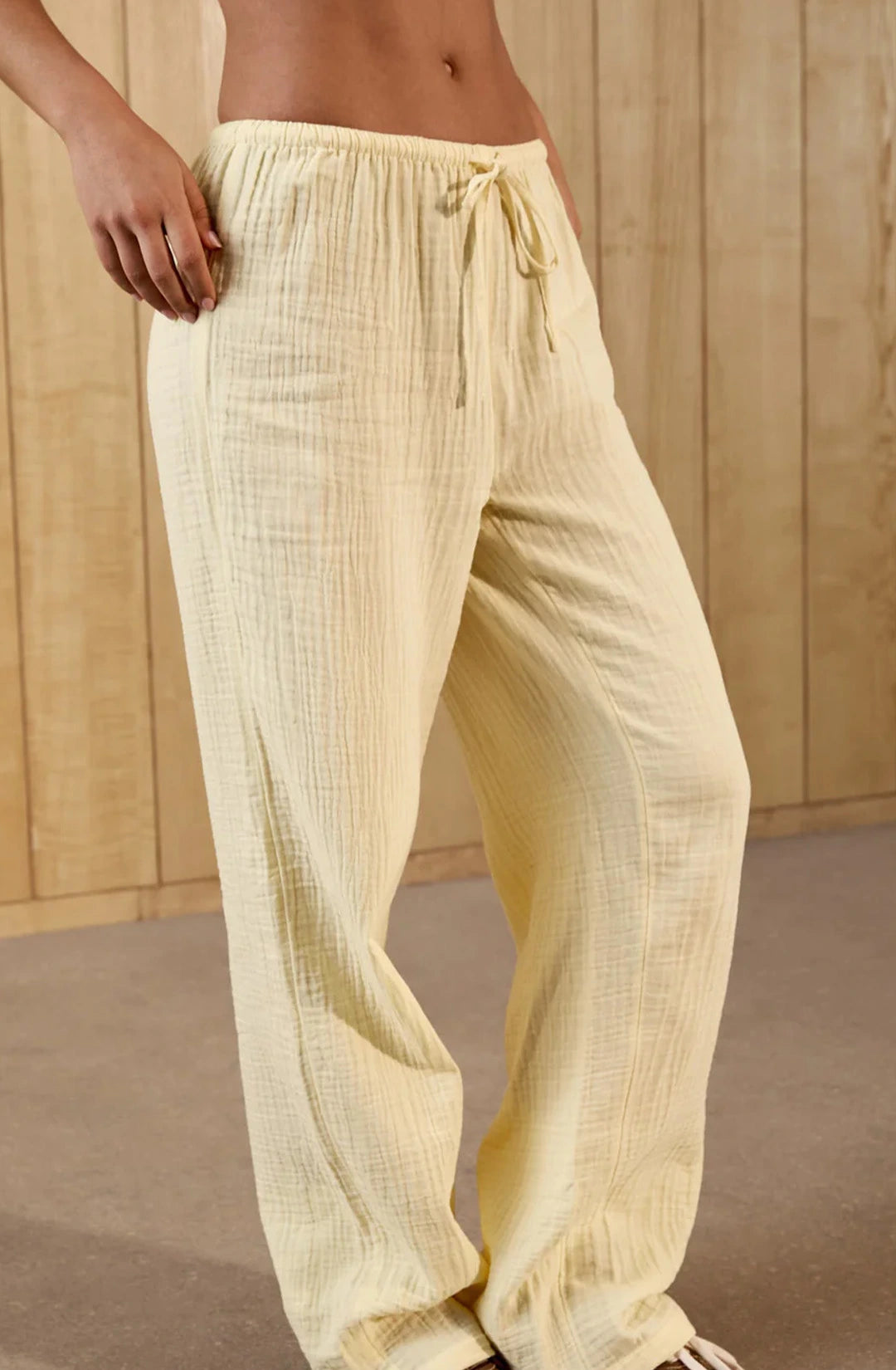 Light yellow pants with a drawstring waist against a wooden background