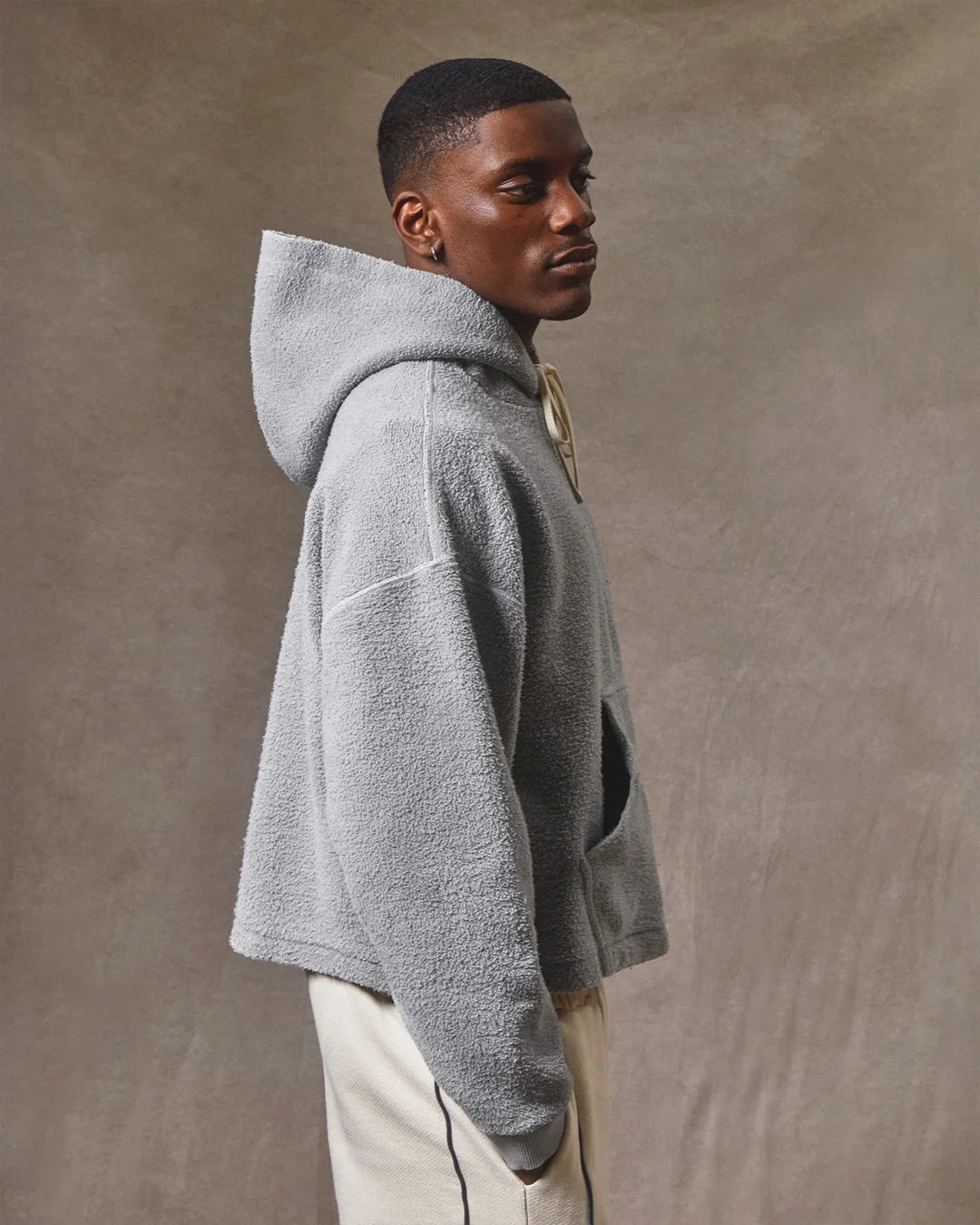 Man wearing a gray hoodie against a brown background