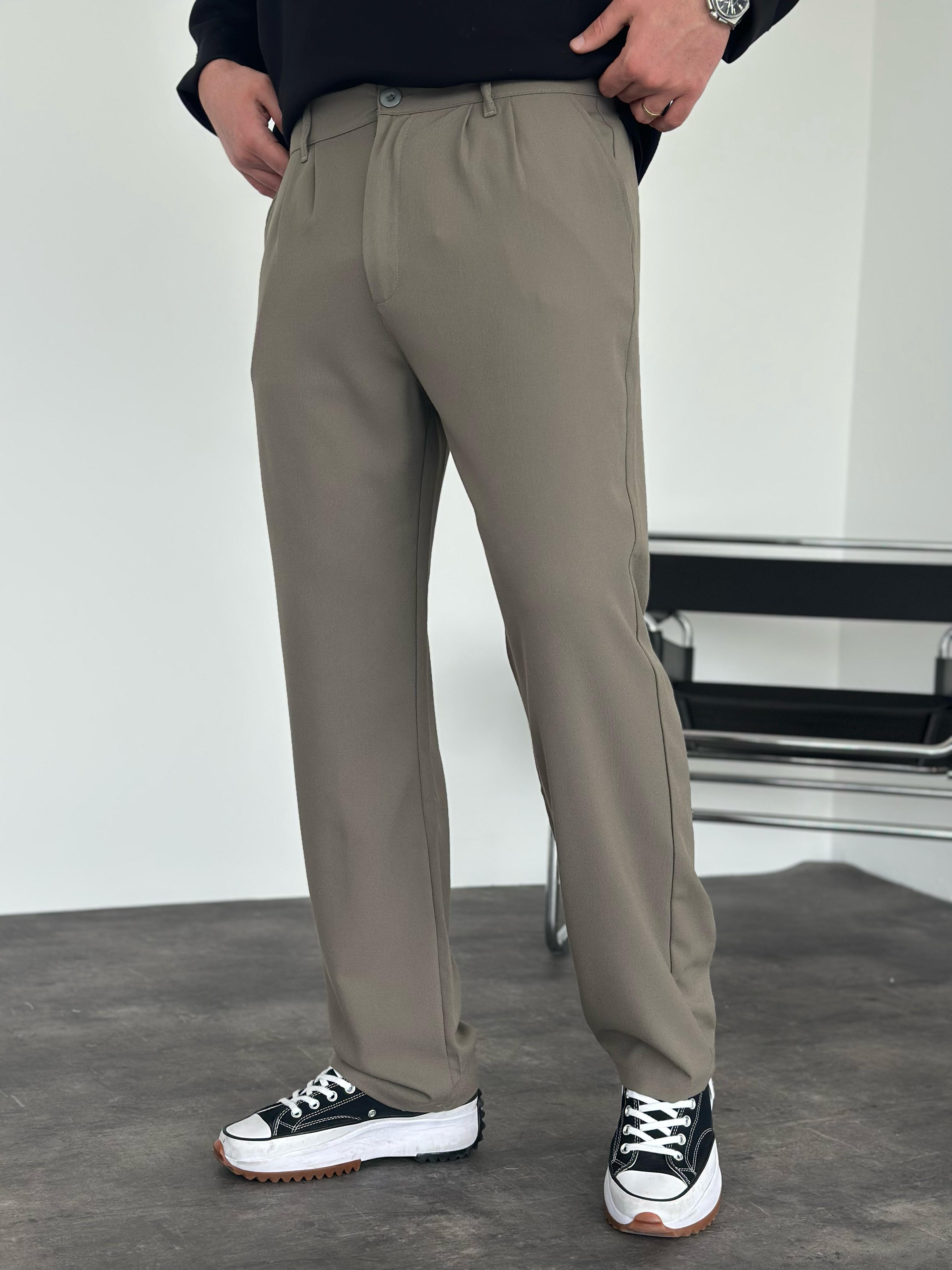 Person wearing beige pants with a white background